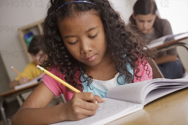 Writing girl (10-11) with girl (12-13) and boy (10-11) in background. 
Photo : Rob Lewine