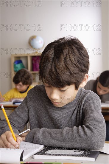 Writing boy (12-13) with boy (10-11) and girl (12-13) in background. 
Photo : Rob Lewine