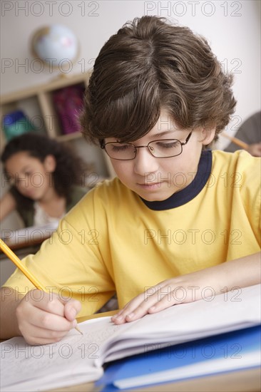 Writing boy (10-11) with girl (10-11) in background. 
Photo : Rob Lewine