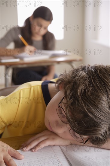 Boy (10-11) napping on desk with girl (12-13) in background. 
Photo : Rob Lewine