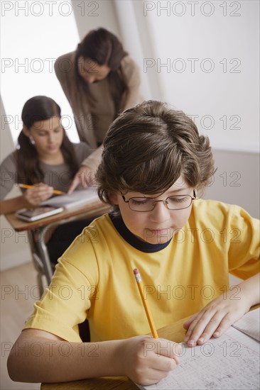 Writing boy (10-11) with girl (12-13) and teacher in background. 
Photo : Rob Lewine