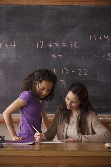 Schoolgirl (10-11) and teacher with blackboard in background. 
Photo: Rob Lewine