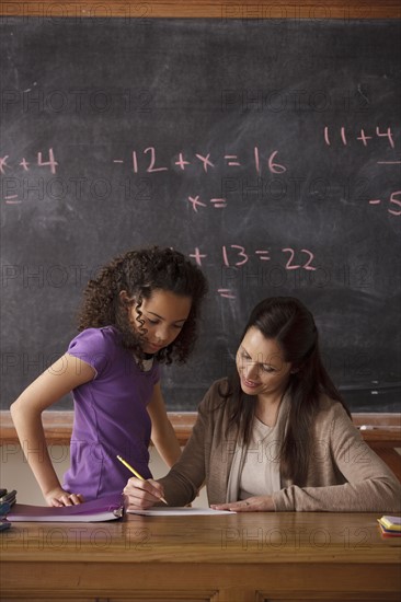 Schoolgirl (10-11) and teacher with blackboard in background. 
Photo : Rob Lewine