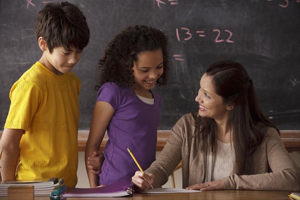 Teacher explaining exercise to schoolgirl (10-11) and schoolboy (12-13). 
Photo : Rob Lewine