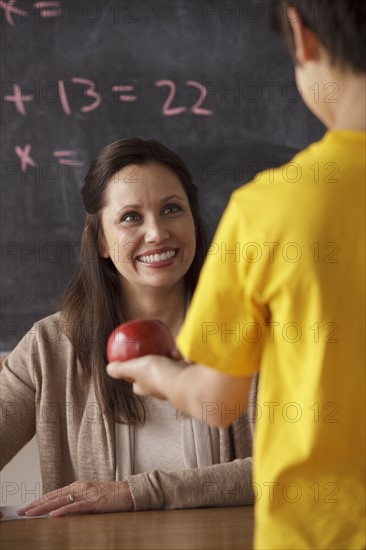 Schoolboy (12-13) giving apple to his teacher. 
Photo : Rob Lewine