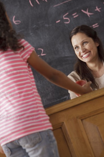 Schoolgirl (10-11) giving apple to his teacher. 
Photo: Rob Lewine