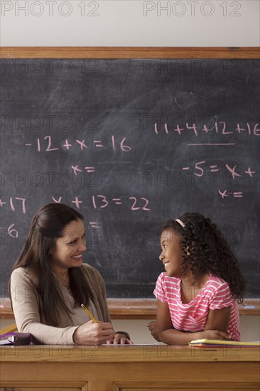 Schoolgirl (10-11) and teacher face to face with blackboard in background. 
Photo : Rob Lewine