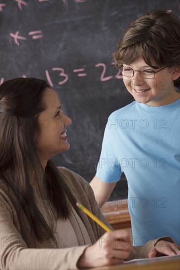 Schoolboy (10-11) and teacher face to face with blackboard in background. 
Photo : Rob Lewine