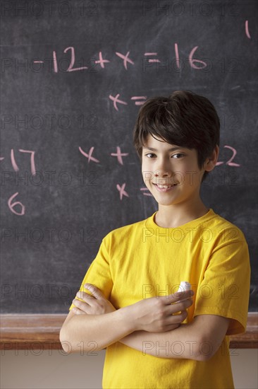 Portrait of schoolboy (12-13) standing in front of blackboard during math classes. 
Photo: Rob Lewine