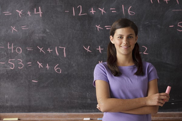 Portrait of schoolgirl (12-13) standing in front of blackboard during math classes. 
Photo : Rob Lewine