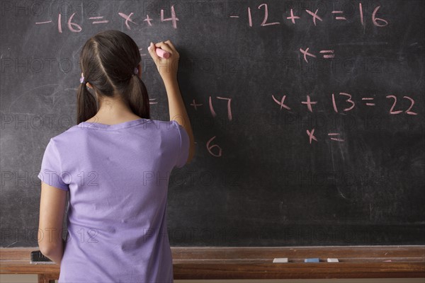 Portrait of schoolgirl (12-13) standing in front of blackboard during math classes. 
Photo : Rob Lewine