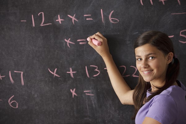 Portrait of schoolgirl (12-13) standing in front of blackboard during math classes. 
Photo : Rob Lewine