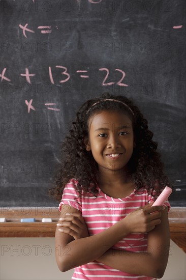 Portrait of schoolgirl (10-11) standing in front of blackboard during math classes. 
Photo : Rob Lewine