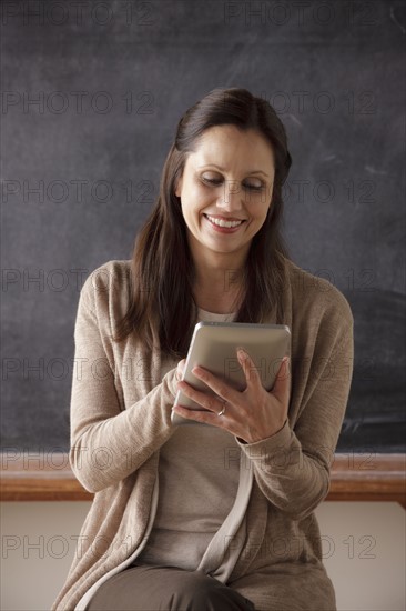 Teacher in classroom holding digital tablet. 
Photo : Rob Lewine