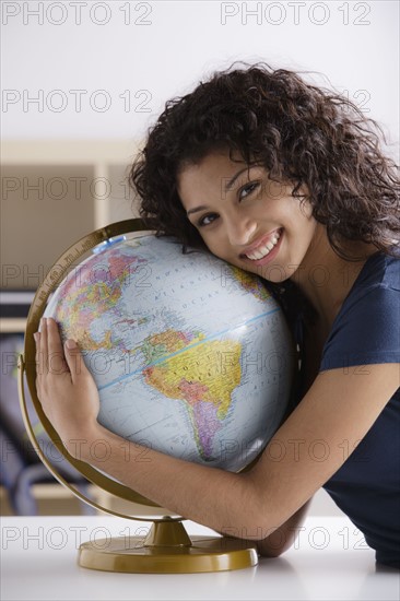 Portrait of teenage girl (16-17) with globe. 
Photo : Rob Lewine