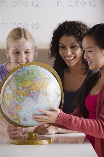 Portrait of teenage girls (14-15, 16-17) with globe. 
Photo: Rob Lewine