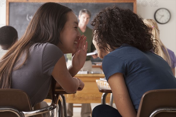 Teenage girls (14-15,16-17) whispering in classroom. 
Photo : Rob Lewine