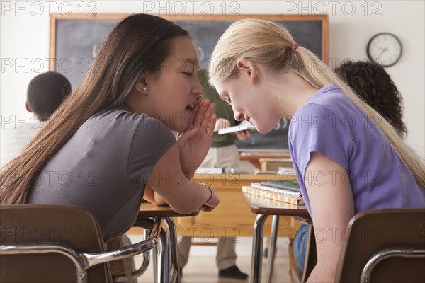 Teenage girls (14-15,16-17) whispering in classroom. 
Photo : Rob Lewine