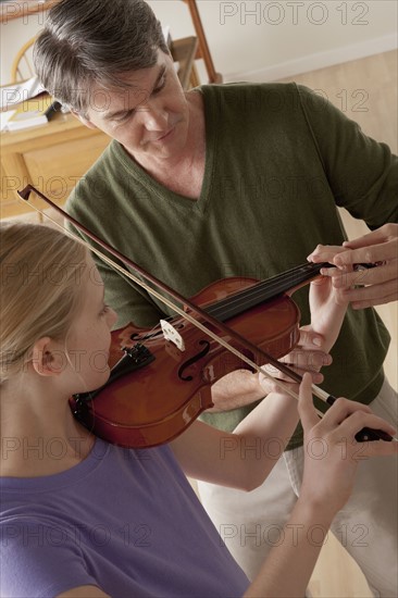 Teacher showing to teenage girl (14-15) how to play violin.
Photo: Rob Lewine