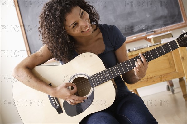 Teenage girl (16-17) playing guitar. 
Photo : Rob Lewine