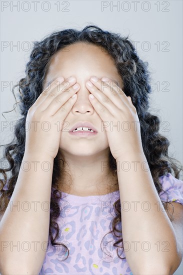 Girl (8-9) covering her eyes, studio shot. 
Photo : Rob Lewine
