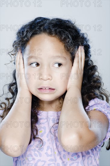 Girl (8-9) covering her ears, studio shot. 
Photo: Rob Lewine