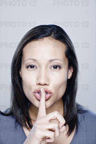 Portrait of young woman with finger on her lips, studio shot.
Photo: Rob Lewine