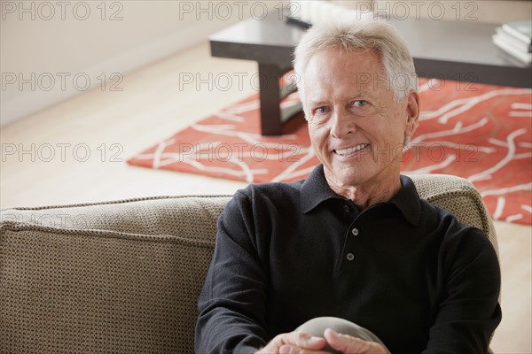 Portrait of smiling senior man sitting on sofa. 
Photo: Rob Lewine