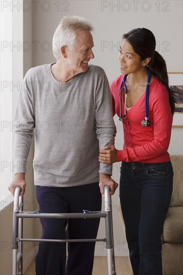 Young female nurse taking care of senior man with walker. 
Photo : Rob Lewine