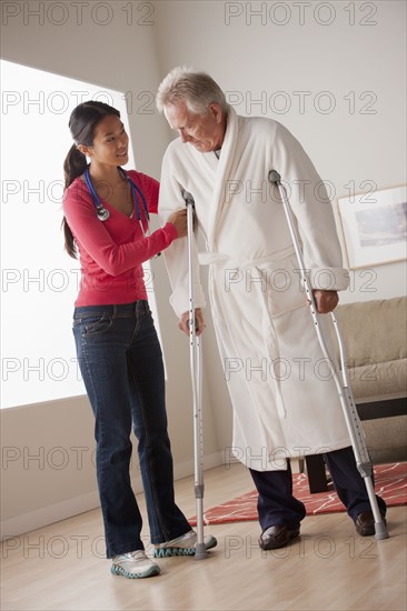 Female nurse helping senior man with crutches. 
Photo: Rob Lewine