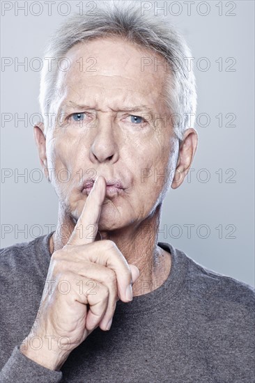 Portrait of senior man with finger on his lips, studio shot.
Photo: Rob Lewine