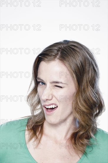 Portrait of young woman blinking eye, studio shot. 
Photo: Rob Lewine