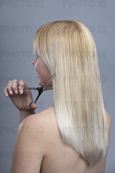 Woman cutting hair, studio shot. 
Photo : Mark de Leeuw