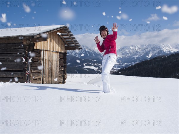 Austria, Maria Alm, Woman at top of mountain enjoying snowball fight. 
Photo: Mark de Leeuw