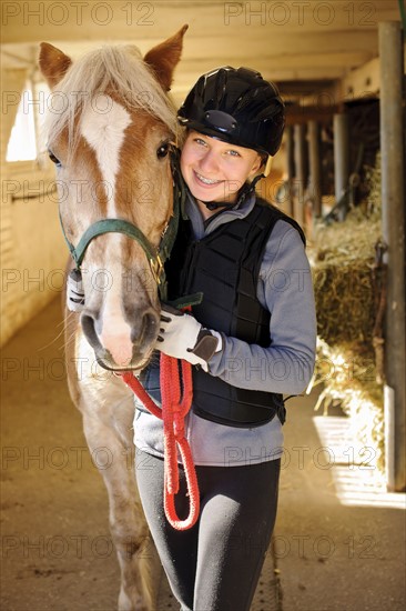 Portrait of teenage girl (16-17) with horse in stable.
Photo : Elena Elisseeva