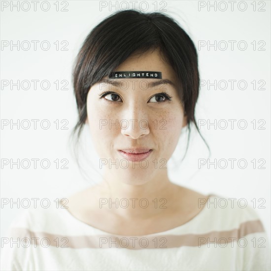 Portrait of young woman with word 'enlightenment' on forehead, studio shot. 
Photo : Jessica Peterson