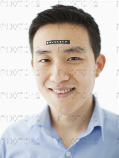 Portrait of young man with word educated on forehead, studio shot. 
Photo : Jessica Peterson
