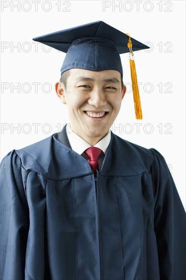 Portrait of young man in graduation gown, studio shot. 
Photo: Jessica Peterson