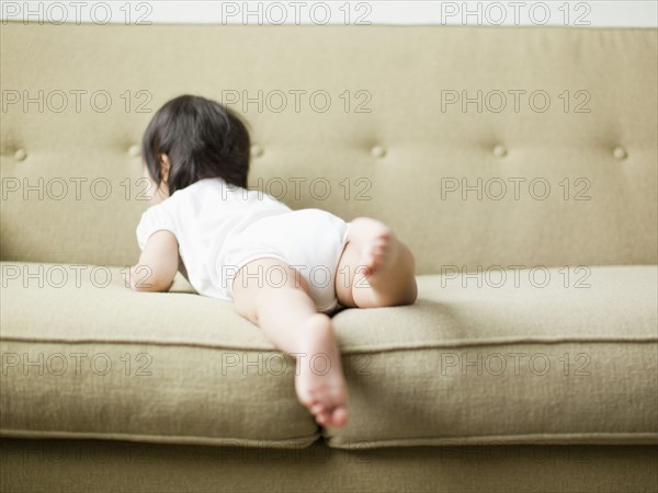 Baby girl (12-17 months) crawling on sofa. 
Photo: Jessica Peterson