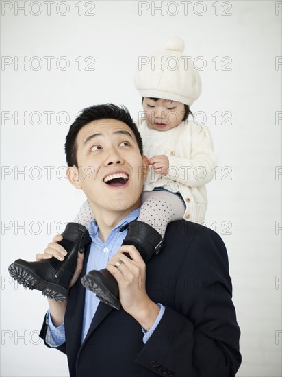 Father carrying baby girl (12-17 months) on shoulders. 
Photo : Jessica Peterson