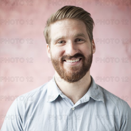 Portrait of smiling young man against pin background. 
Photo : Jessica Peterson