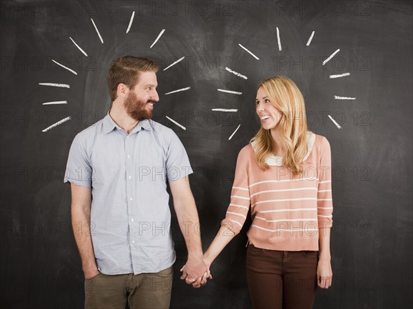 Young couple with blackboard in background, studio shot. 
Photo : Jessica Peterson