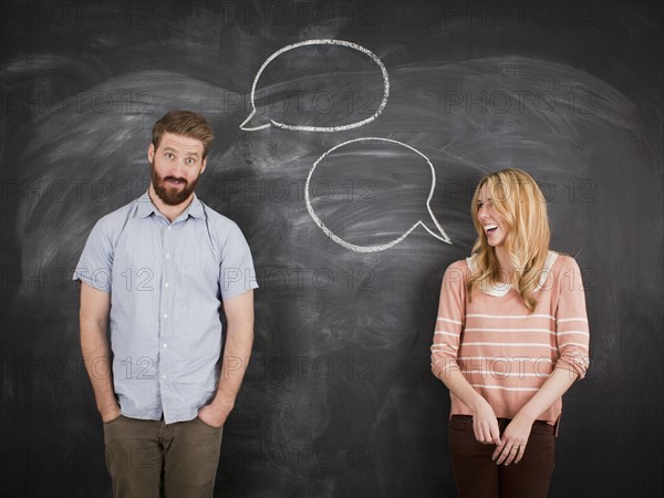 Young couple with speech bubble on blackboard, studio shot. 
Photo : Jessica Peterson