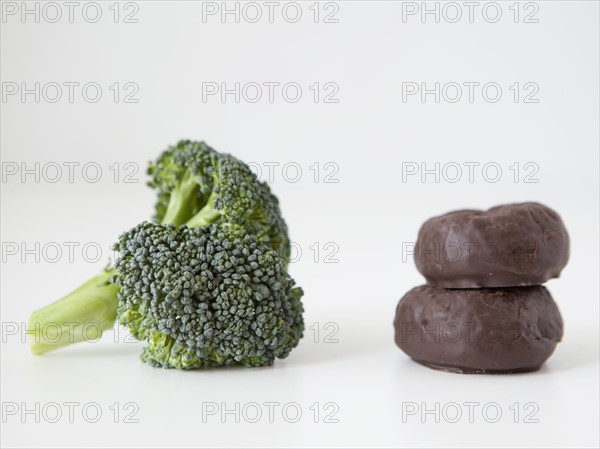 Broccoli and chocolate cookies on white background, studio shot. 
Photo: Jessica Peterson