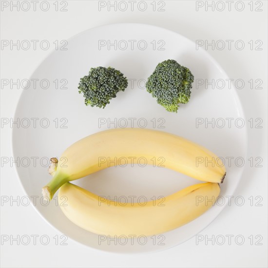 Fruit and vegetable face on plate, studio shot. 
Photo : Jessica Peterson