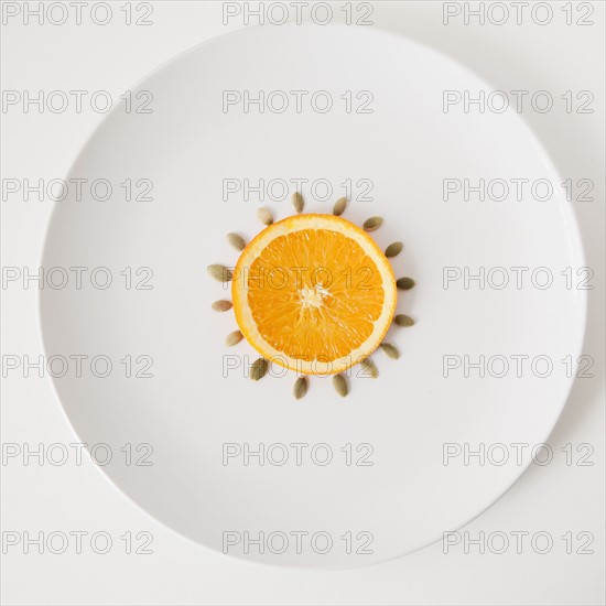 Slice of orange and seeds on plate, studio shot. 
Photo : Jessica Peterson