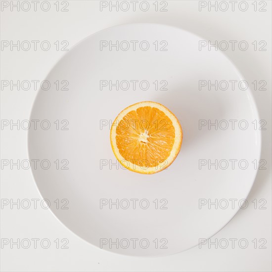 Half of orange on plate, studio shot. 
Photo : Jessica Peterson