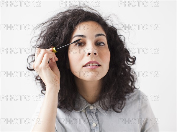 Beautiful young woman applying mascara. 
Photo : Jessica Peterson