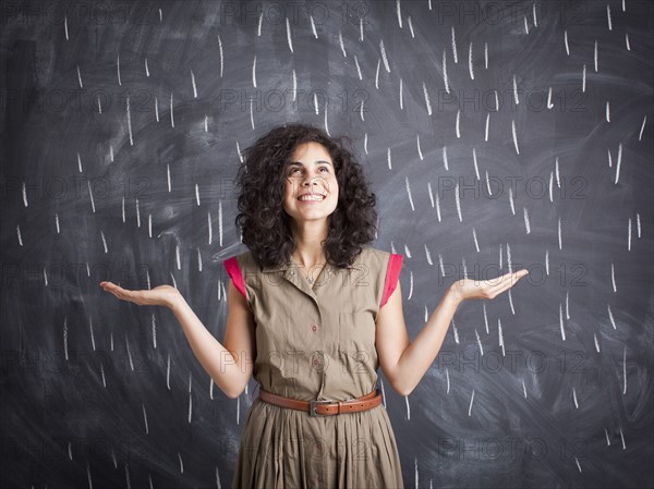 Young teacher posing against blackboard with V marks imitating rain. 
Photo : Jessica Peterson