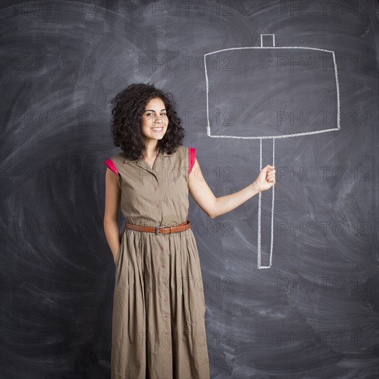 Young teacher posing against blackboard with blank banner written in chalk. 
Photo: Jessica Peterson